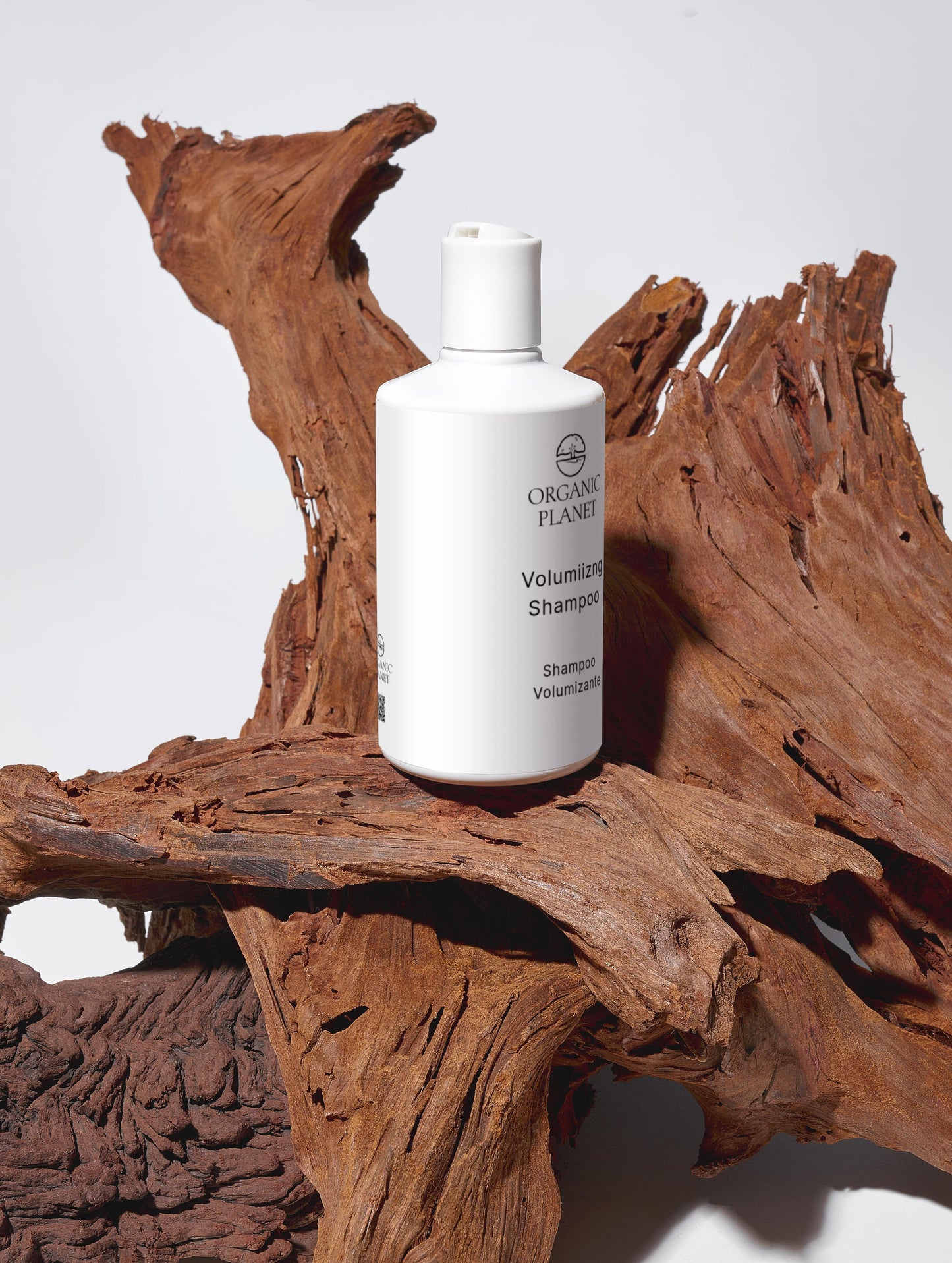 White shampoo bottle labeled 'Organic Plant' on a wooden surface. Nourish and Volumize Shampoo thoroughly cleanses hair while maintaining its softness. It strengthens each strand and adds noticeable volume with the help of Hydrolysed Wheat Protein. Hydrating ingredients such as Glycerin, Betaine, and Xylitol deeply condition and nourish the hair. Mild surfactants like Sodium Coco-Sulfate, Coco-Glucoside, and Cocamidopropyl Betaine deliver effective cleansing, while Brassica Alcohol and Brassicyl Isoleucinat