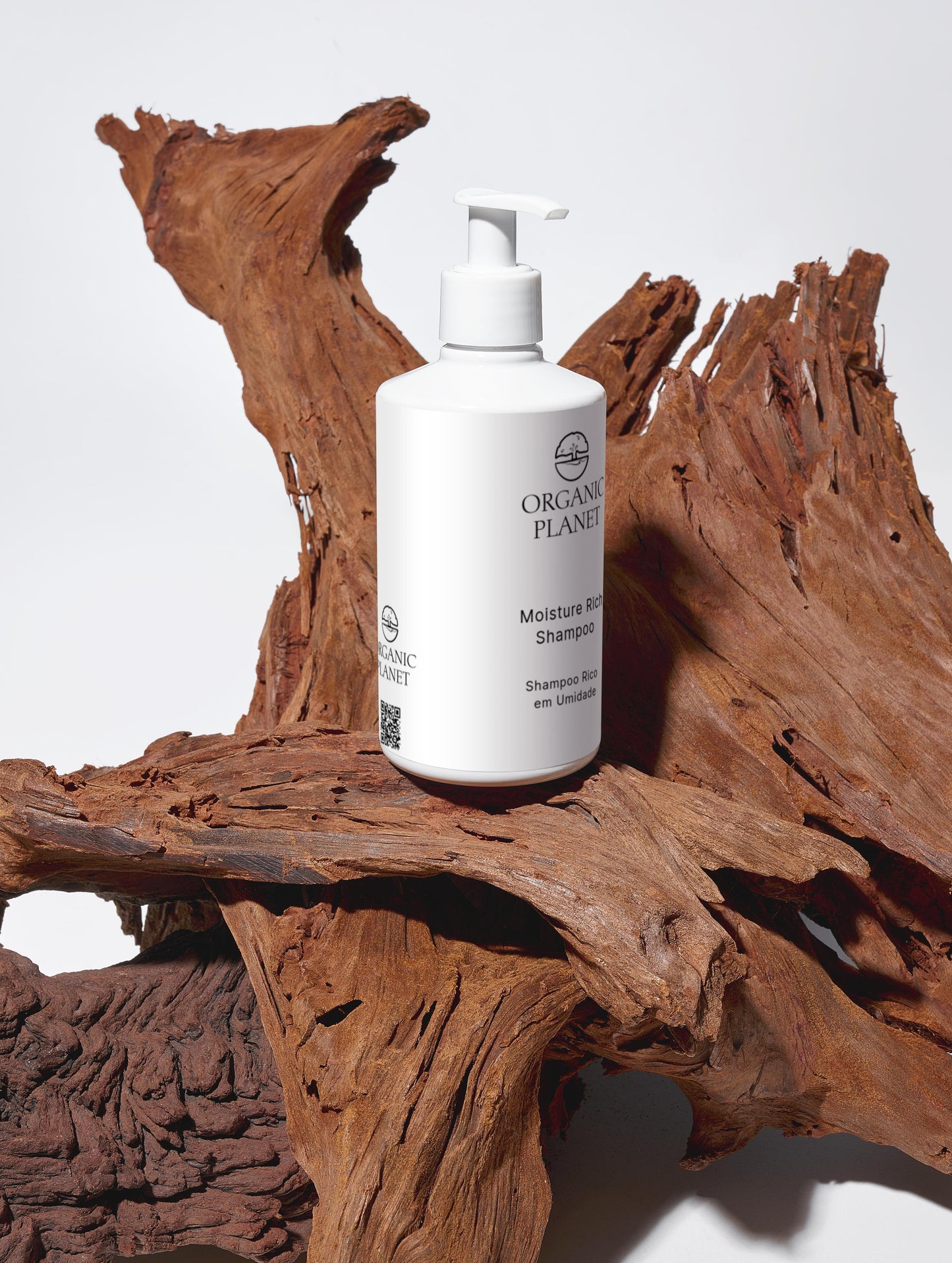 White shampoo bottle labeled 'Organic Planet' on a wooden surface. This vegan shampoo gently cleans and moisturizes hair using organic Aloe Vera and botanical extracts. Free from sulfates, parabens, and silicones, it is ECOCERT COSMOS certified and comes in eco-friendly packaging. It leaves hair soft, smooth, and full of volume while supporting sustainable beauty.