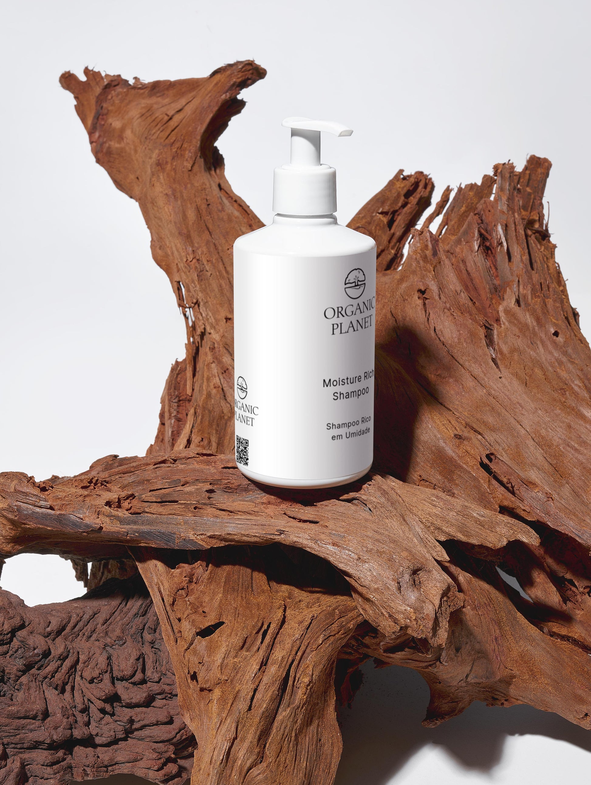 White shampoo bottle labeled 'Organic Planet' on a wooden surface. This vegan shampoo gently cleans and moisturizes hair using organic Aloe Vera and botanical extracts. Free from sulfates, parabens, and silicones, it is ECOCERT COSMOS certified and comes in eco-friendly packaging. It leaves hair soft, smooth, and full of volume while supporting sustainable beauty.