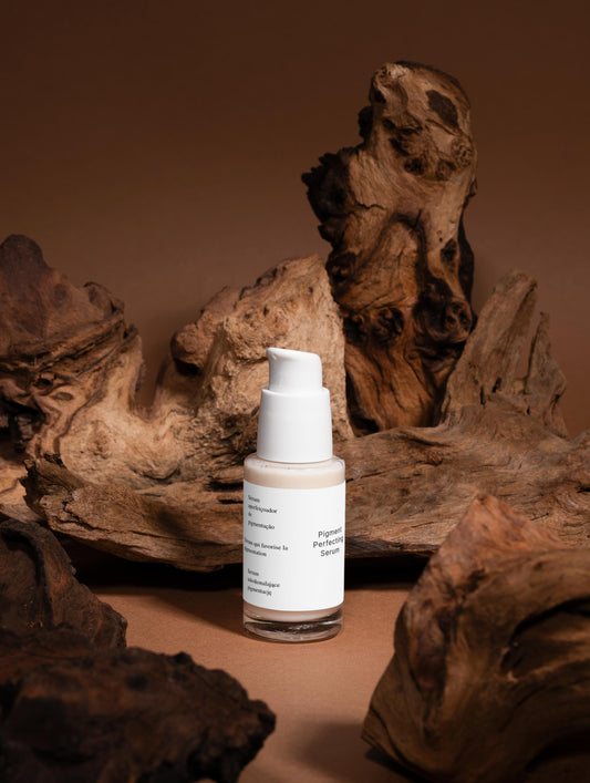A targeted serum that reduces dark spots and evens skin tone for a brighter, more uniform complexion. The lightweight formula hydrates and soothes while tackling pigmentation concerns. Finished with an elegant blend of vetiver, wood, and almond notes. Skincare bottle with a label on a brown background with natural wood elements.